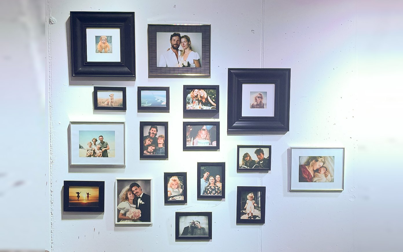 The Family Wall installation: around twenty framed AI-generated family photos on a concrete wall